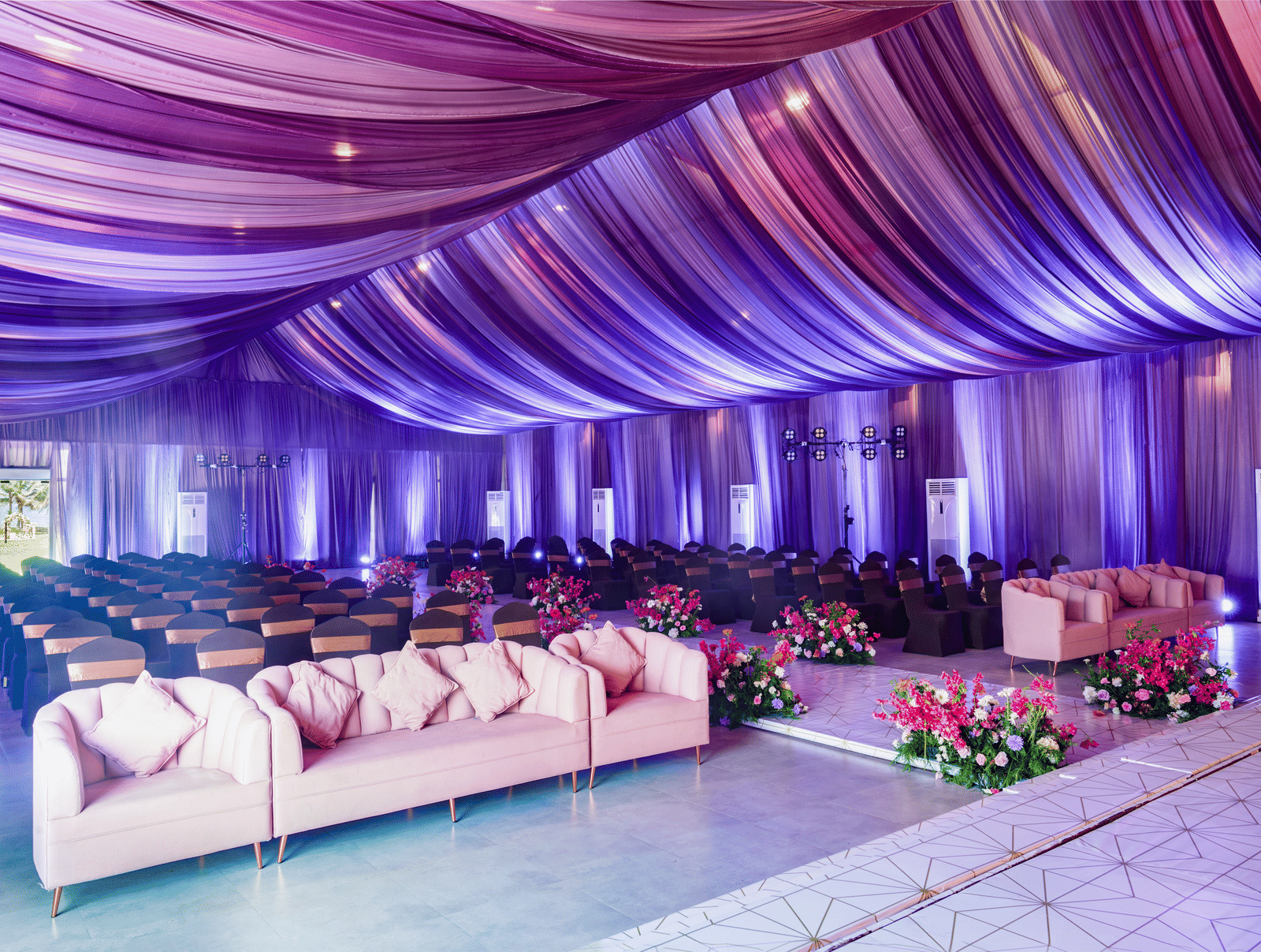 An indoor hall featuring purple draped ceiling, sofa seating rows, and floral aisle decor - Grande Bay Resort & Spa, Mamallapuram