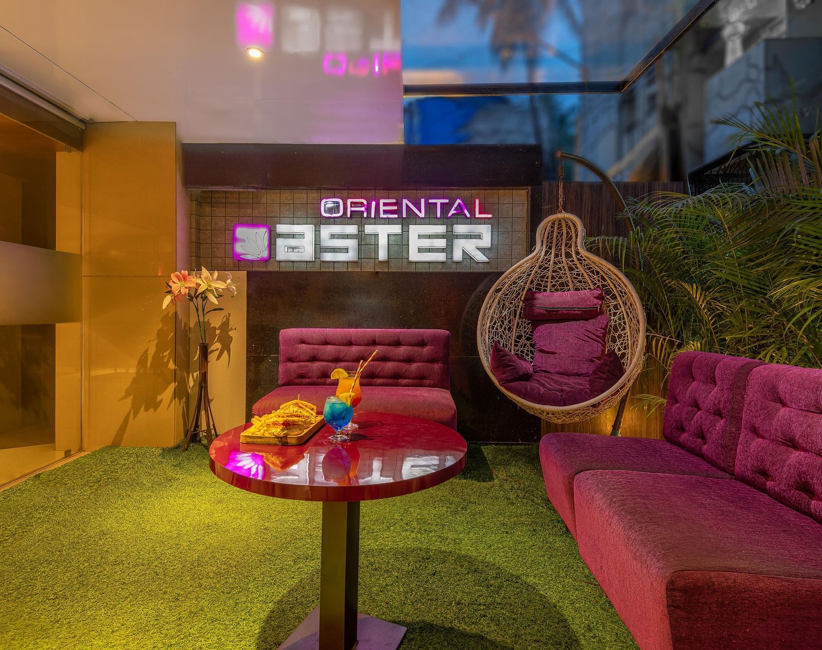 View of the lobby area at Oriental Aster, Mumbai, featuring cushioned sofas arranged around a table and a signboard displaying 'Oriental Aster'.