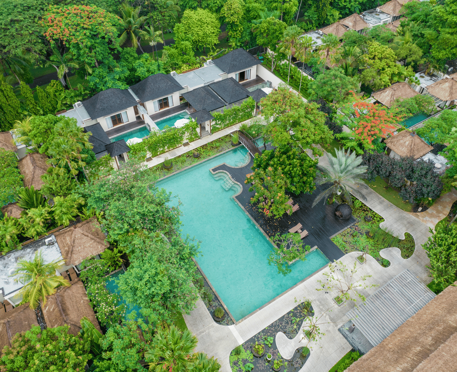 Overhead view of a hotel with a large, tree-lined pool area.