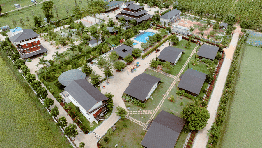 An aerial bird's-eye view of the resort layout showing individual cottages, pathways, trees, and a swimming pool | Vintage Trails By Ilara