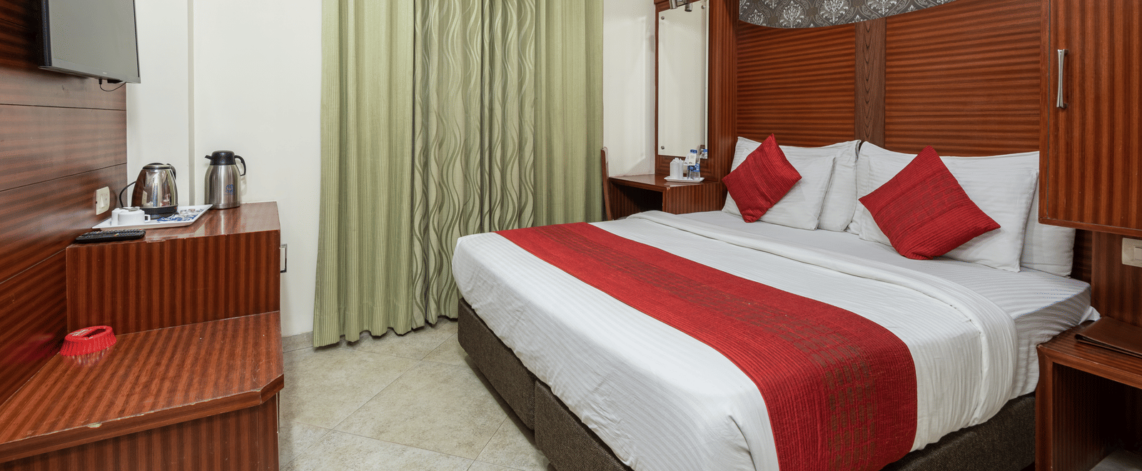 Side view of a deluxe room featuring a king size bed, a TV, and a tea & coffee maker on the table at DLS Hotels The Rock Castle.
