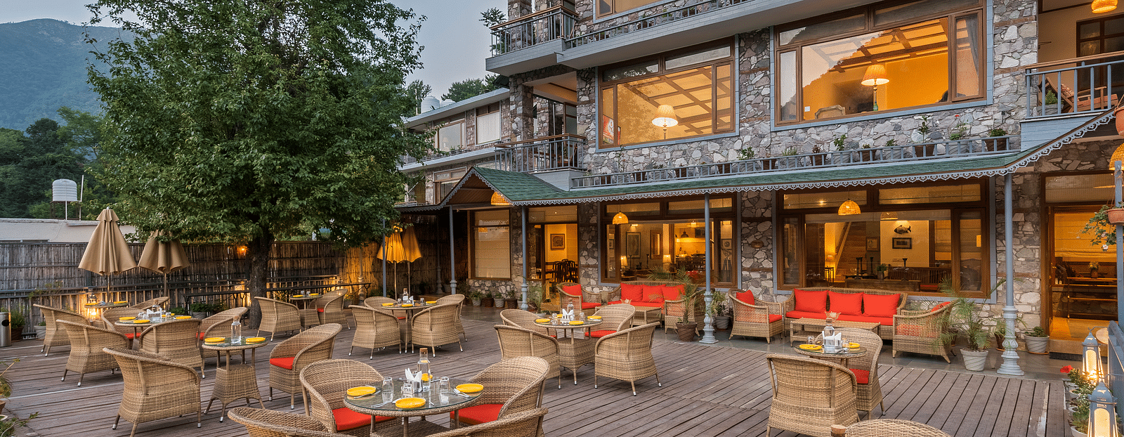 Front view of hotel facade featuring seating arrangements, surrounded by mountains.