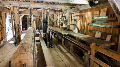 The interior of a traditional sawmill features wooden beams, machinery, and a long cutting track | Chatham Saw Mill Port Blair