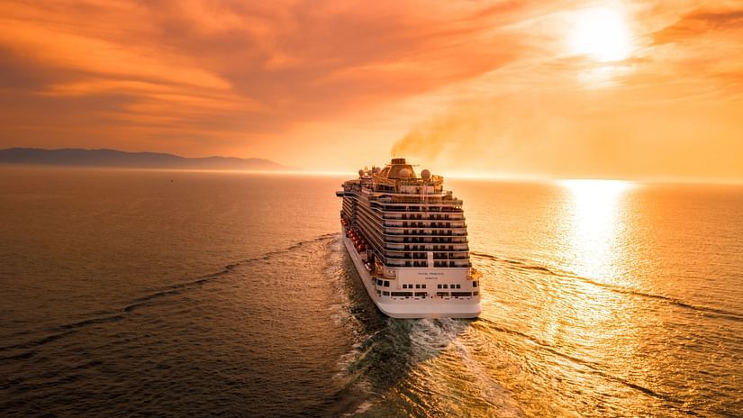 A cruise in the ocean with the sun setting in the background