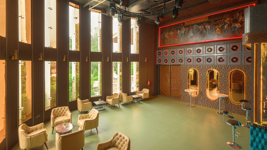 Stylish bar and lounge with cushioned seating, patterned flooring, decorative wall panels and warm ambient lighting.