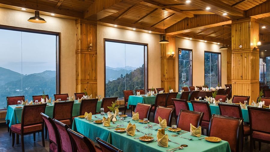  An elegant dining space with warm wooden interiors and expansive windows offering stunning valley views, creating a cozy and luxurious dining experience - Digantaa Resort in Mukteshwar