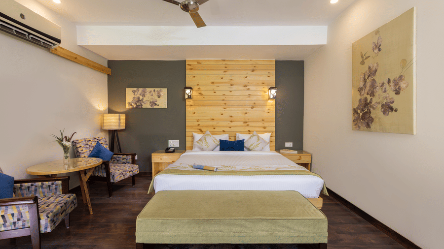 Villas bedroom with bed, a ceiling fan, and wooden furniture  at The Golden Tusk, Jim Corbett