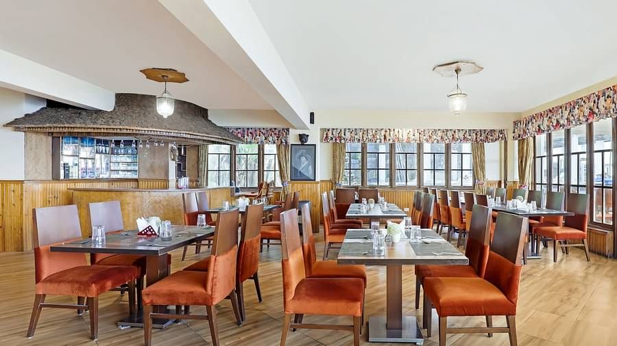 A side view of dining tables and chairs in a closed dining space | Summit Newa Regency & Spa, Pelling