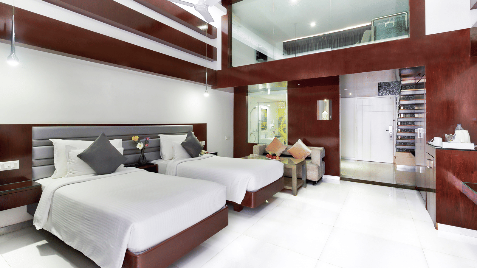 A clean hotel room featuring two beds with white linens, wooden accent walls, and a large window - Grande Bay Resort Booking in Mahabalipuram 