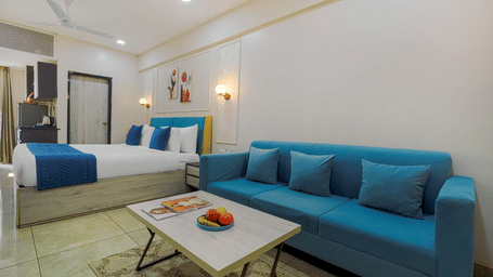 A hotel room at Urban Suites by BluSalzz, Jaipur, featuring a bed with sheets and pillows, a sofa, and a table.
