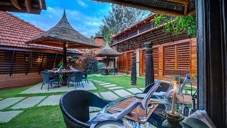 Image of the outdoor restaurant amidst the beautiful garden at the hoysala village resort in hassan