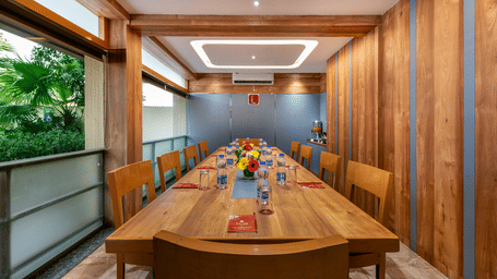 A modern Board Room in  Lords Eco Inn with a long wooden table, wood-paneled walls, and a large window.