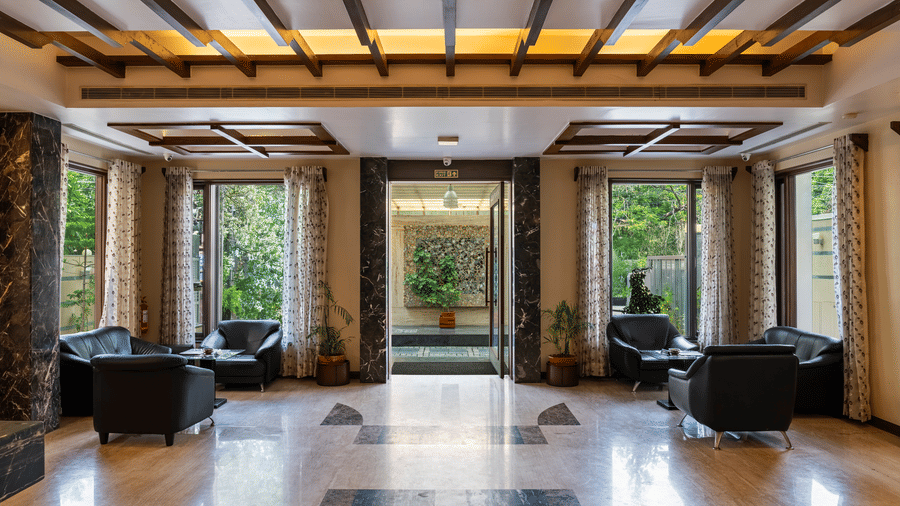 The entrance of the hotel leading to the lobby area, featuring the natural light reflecting on the shiny marble flooring - Amantra Comfort Hotel