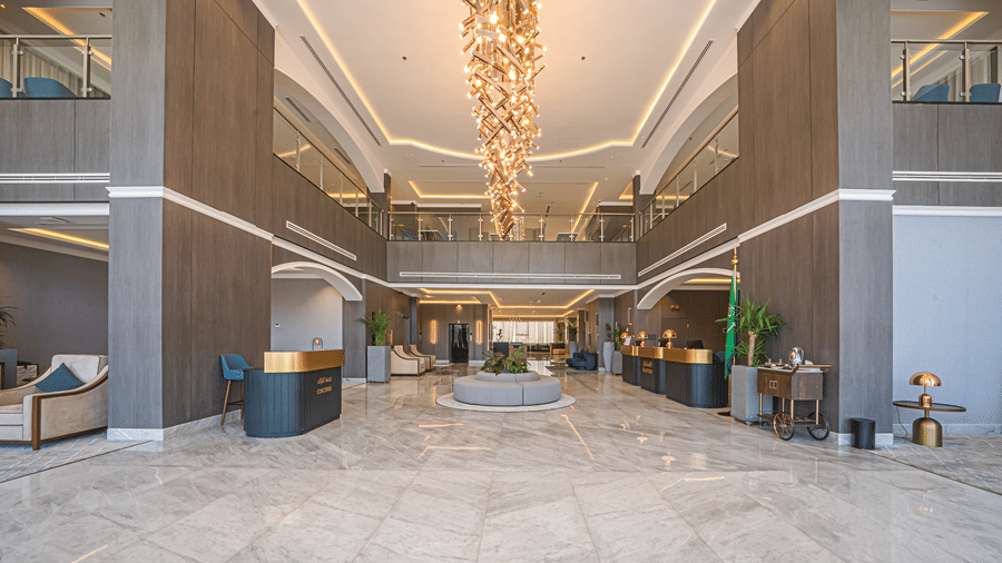 Gran lobby area of Grand Iva Hotel, Abha, seen with a large chandelier, seating areas, reception desk, and an overhead floor.