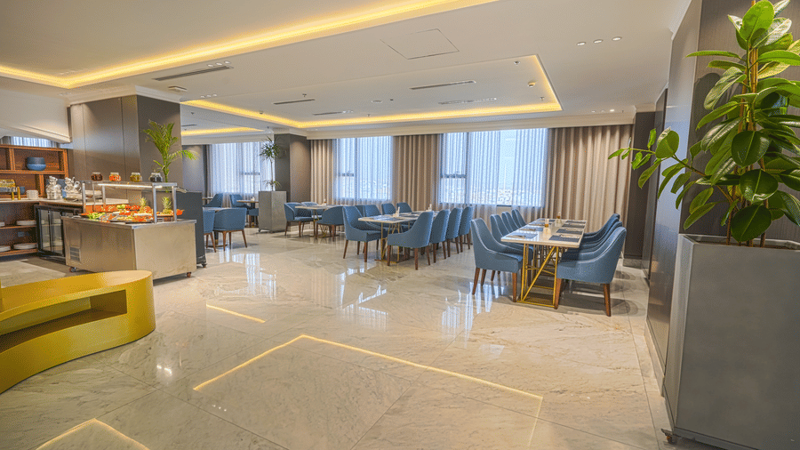 Seating area of the  Nahraan Restaurant at Grand Iva Hotel, Abha, showcasing neatly arranged dining tables with upholstered chairs and table settings, with glass windows in the background offering natural light passage.
