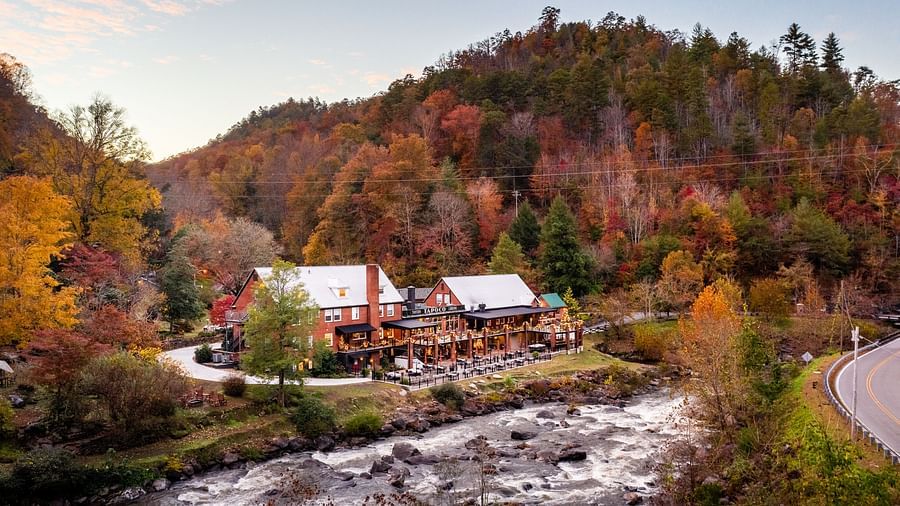a beautiful facade image of the resort surrounded by colorful autumn trees and a river flowing in front of it - Historic Tapoco Lodge