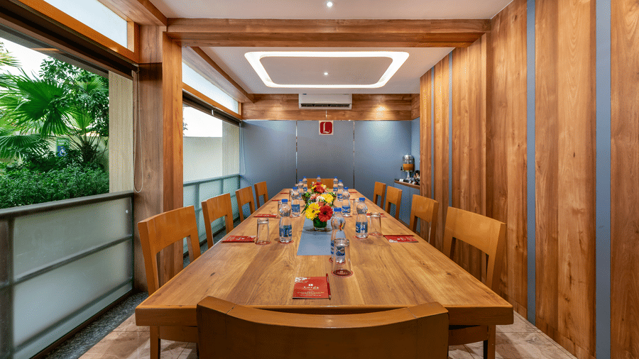A modern Board Room in  Lords Eco Inn with a long wooden table, wood-paneled walls, and a large window.
