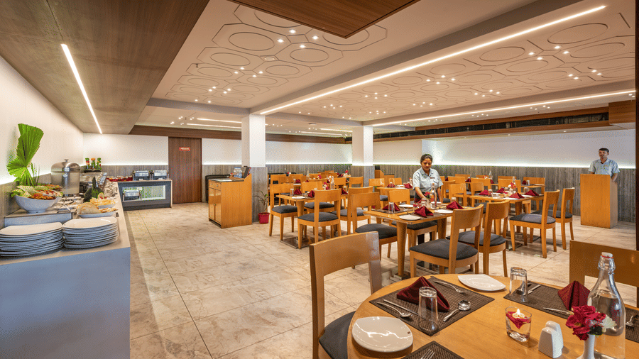 Lords Eco Inn dining area with multiple set tables, chairs, and a buffet counter.