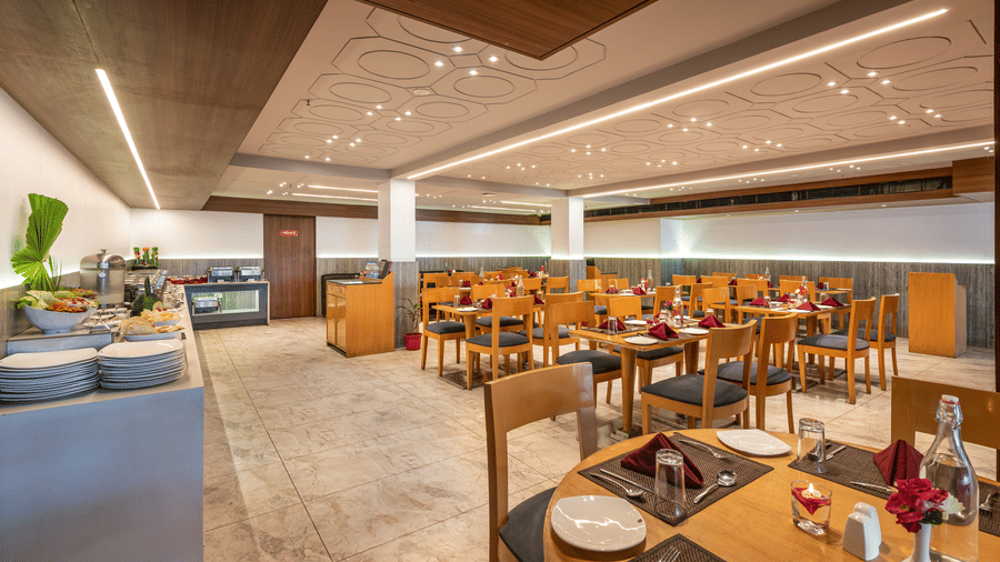 Lords Eco Inn dining area with multiple set tables, chairs, and a buffet counter.