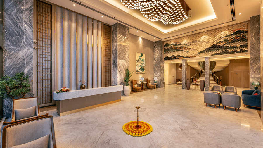 Lobby featuring a reception desk, decorative ceiling design, and a traditional marigold rangoli at Lords Inn Somnath, welcoming guests.