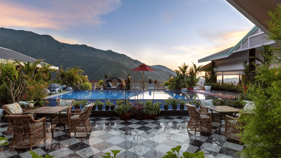 Outdoor poolside seating terrace set against dramatic green mountain peaks at Mayfair Manor, Jungpana.
