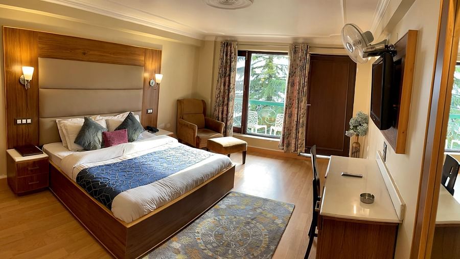 A bedroom with a plush bed and glass windows with sweeping Himalayan views | Mongas Hotel & Resort, Dalhousie