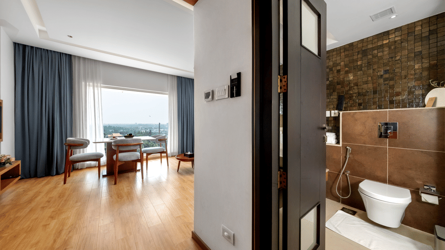 A view from a doorway showing a living area with a dining setup on the left and a tiled bathroom on the right at Tiara by MPS.