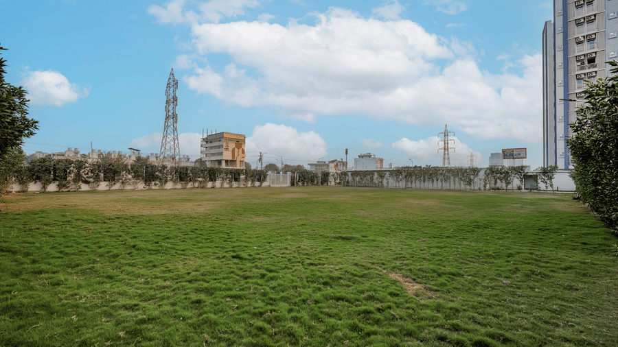 The grassy lawn area at Urban Suites by BluSalzz, Jaipur, on a partly cloudy day, showing the surrounding buildings and open space.