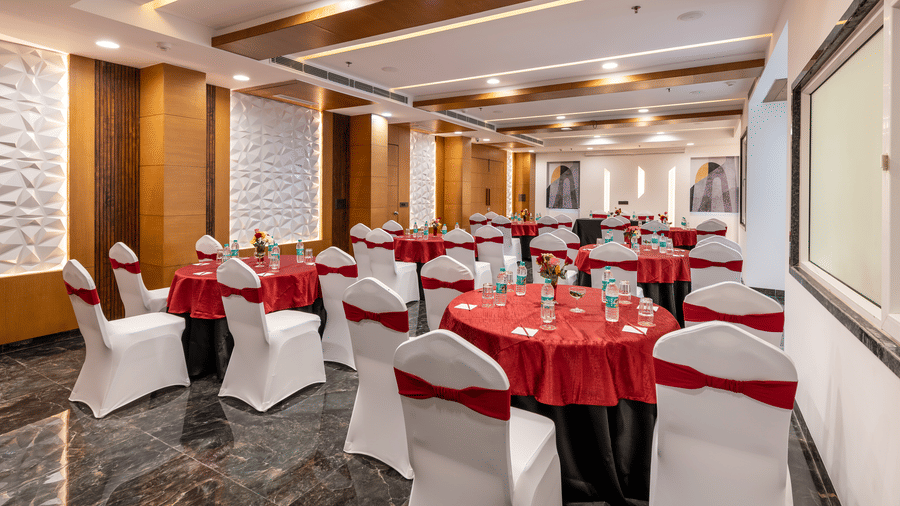 Elegant banquet cluster setup with round tables filled with water bottles on top, red and white covers, perfect for events or conferences.