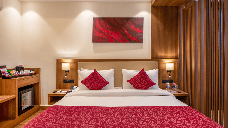 A close up view of a room at Lords Inn Katra featuring a king size bed with a patterned runner, pillows, and a rectangular artwork on the wall.