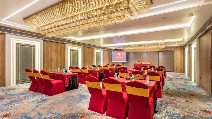 Banquet hall at Lords Inn Sangam, Bhopal set up with red and gold chairs facing a presentation screen, ideal for conferences and corporate events.