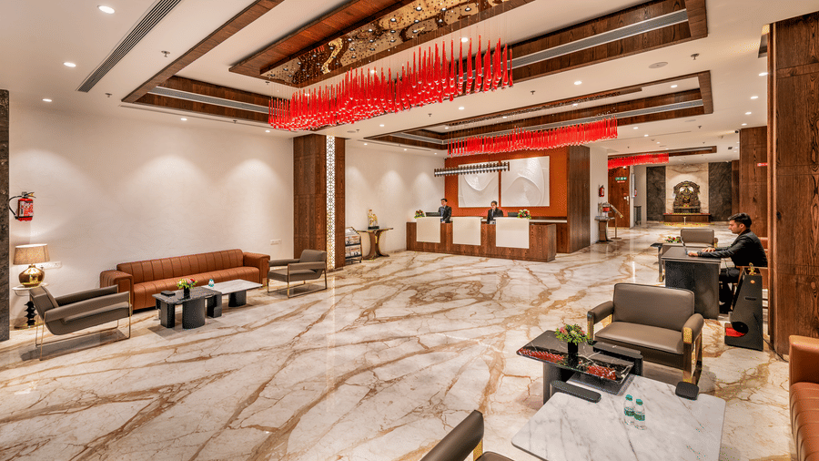  An elegant hotel lobby with marble flooring, contemporary tan seating, and a striking red glass chandelier, leading towards a reception desk - Skkylight Lords Inn, Nanded