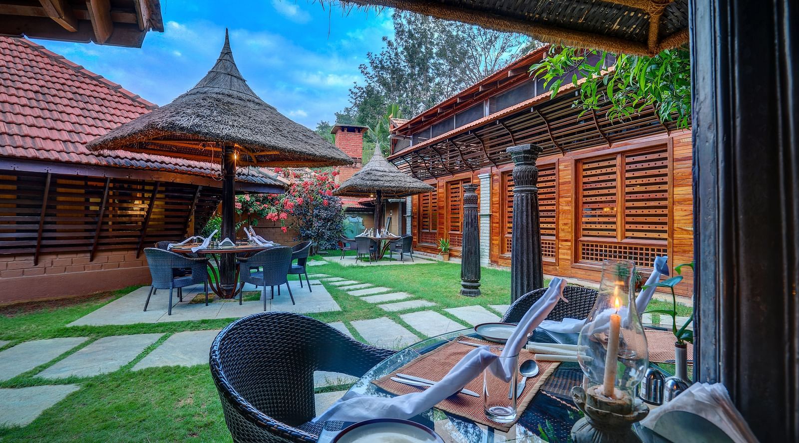 Image of the outdoor restaurant amidst the beautiful garden at the hoysala village resort in hassan