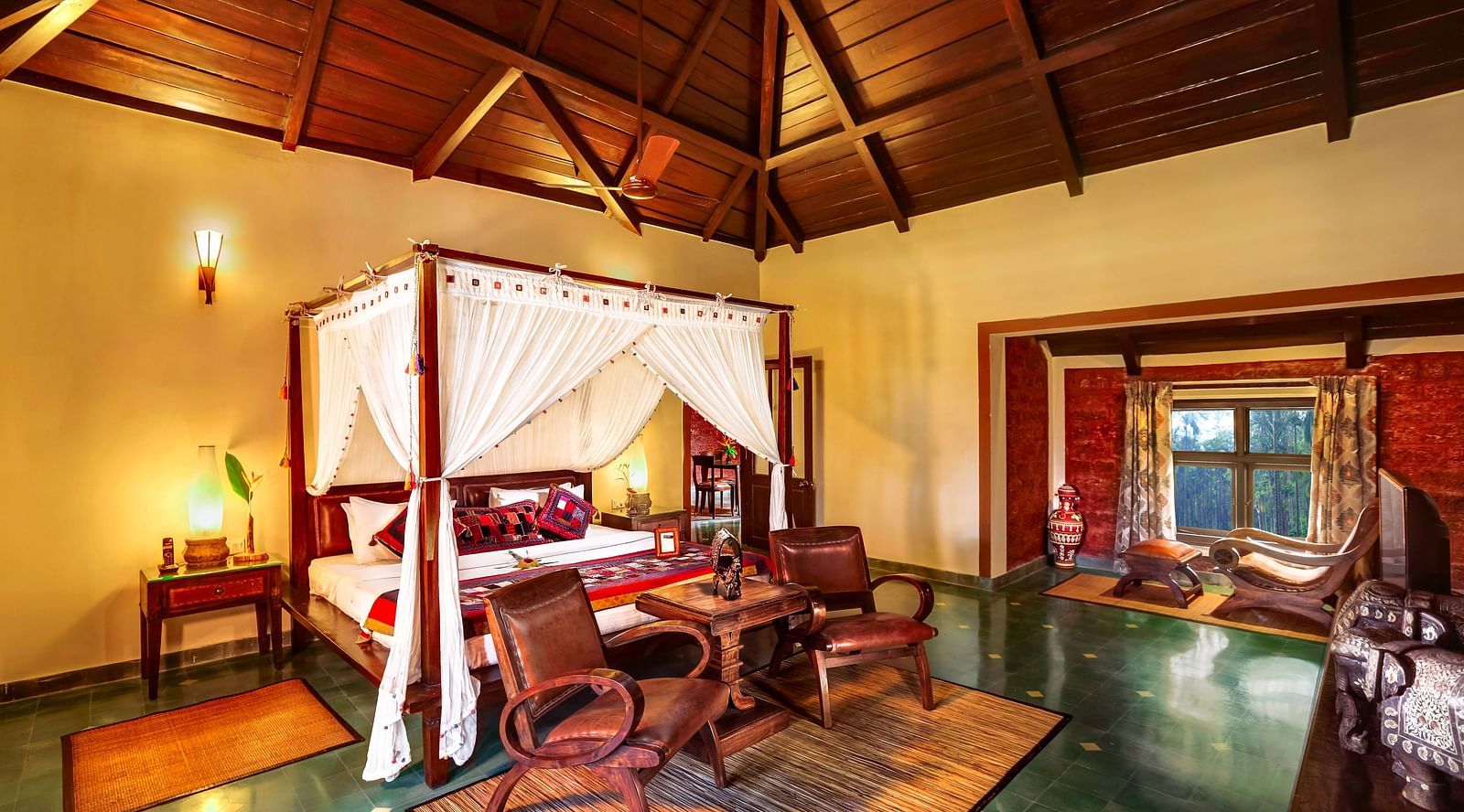 An image of a bedroom with poster bed, some chairs, and a dressing table - Hoysala Village Resort, Hassan