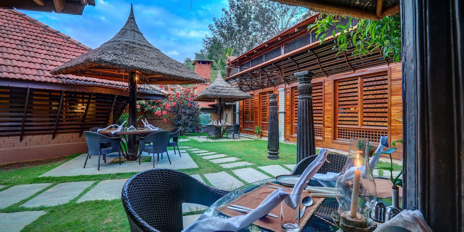 Image of the outdoor restaurant amidst the beautiful garden at the hoysala village resort in hassan