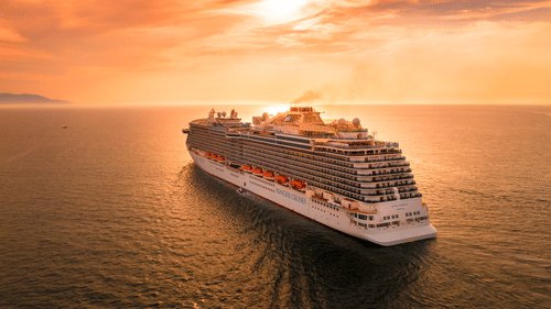 Wondering about Andaman And Nicobar Islands, How To Go there? A cruise ship! it is sailing on a waterbody towards the sunset.