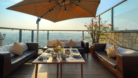 Bluflamingo dine-in at BluSalzz Residence, Amritsar, with dark couches, a dining table, a large umbrella, and a glass railing  sky in the background