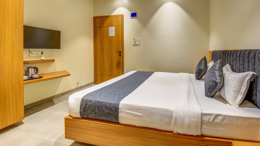 Modern deluxe room featuring a bed, wall-mounted TV, and a compact work desk at VITS Select Nashik Hotels & Resorts