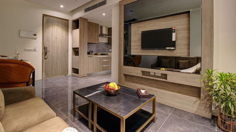 living area inside the Premium Suite with a tv wall mounted, sofas and a coffee table - Rhythm Gurugram