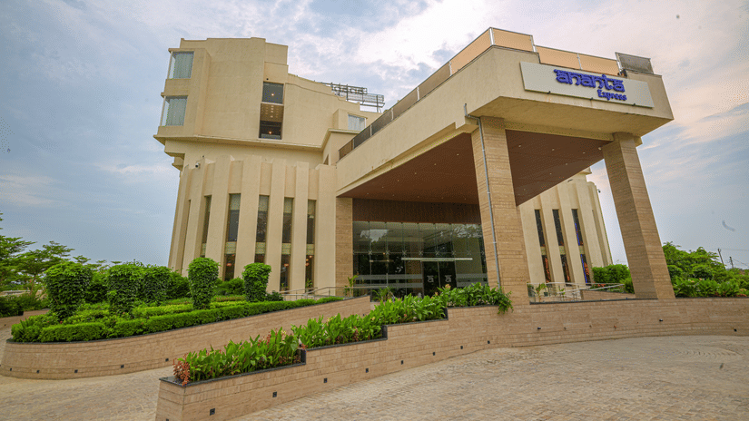 Grand white hotel building with tall columns, landscaped grounds and a covered entrance under a partly cloudy sky.