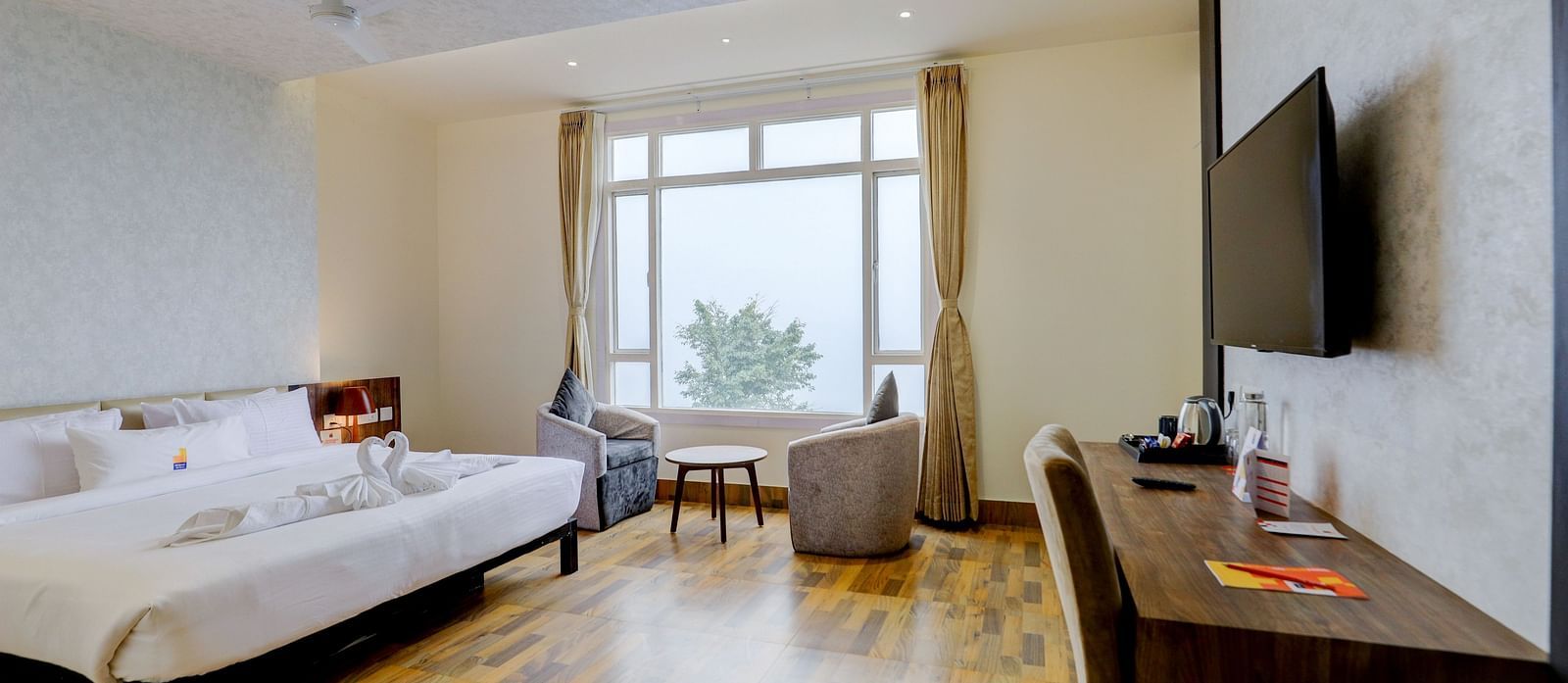 view of a TV and a  king size bed placed next to a window Suite at Banari Regency by Summit, Namchi