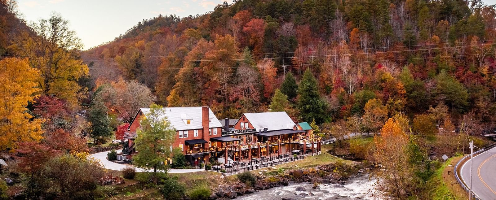 a beautiful facade image of the resort surrounded by colorful autumn trees and a river flowing in front of it - Historic Tapoco Lodge