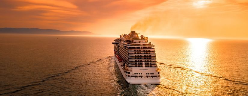 A cruise in the ocean with the sun setting in the background