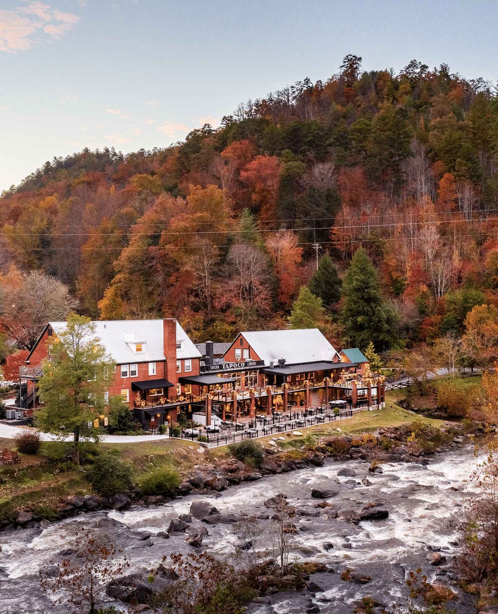 a beautiful facade image of the resort surrounded by colorful autumn trees and a river flowing in front of it - Historic Tapoco Lodge