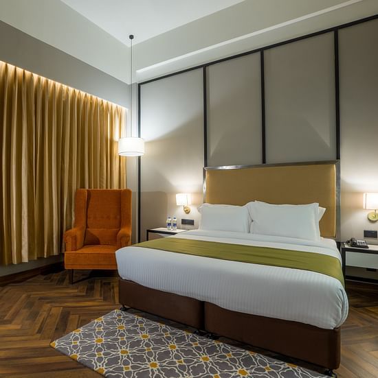double bed and chair in one of the rooms at Hotel Polo Towers Agartala