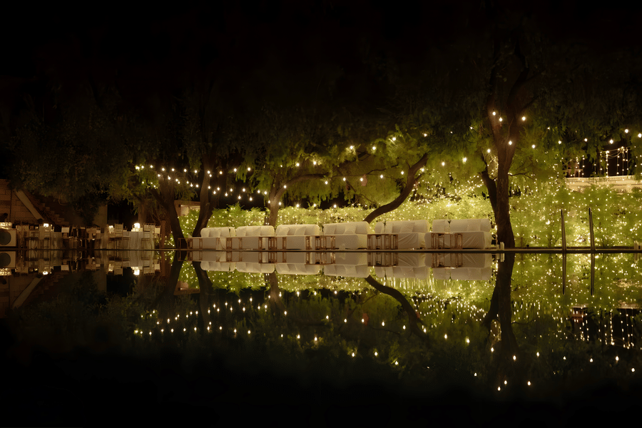 Evening decor with lights reflecting on water at Umaid Palace during Charvi & Dhruv wedding celebrations.