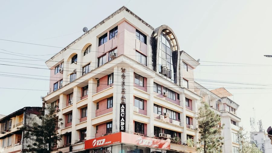 A wide angle view of a lady standing beside a flyover with a building in the backdrop.