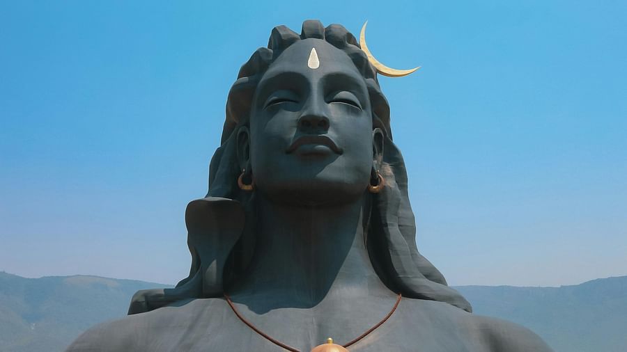 A large bust of Lord Shiva with tourists observing it.