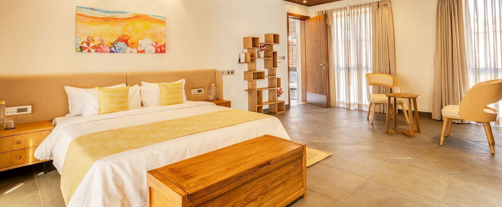 A cosy bedroom with a pitched wooden ceiling, a king-sized bed, soft yellow accents, and natural light filling the space - BluSalzz Villas - Alocassia, Anjuna