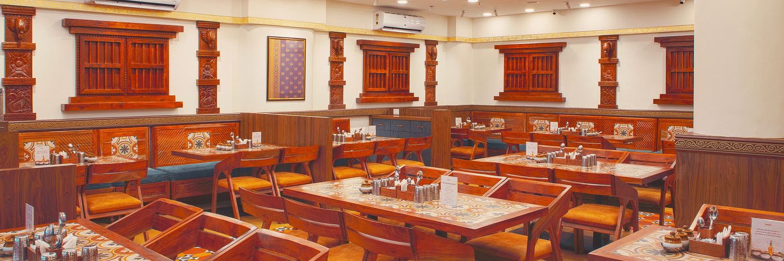 Elegant dining area with rich wooden furniture and modern lighting | Kamats India